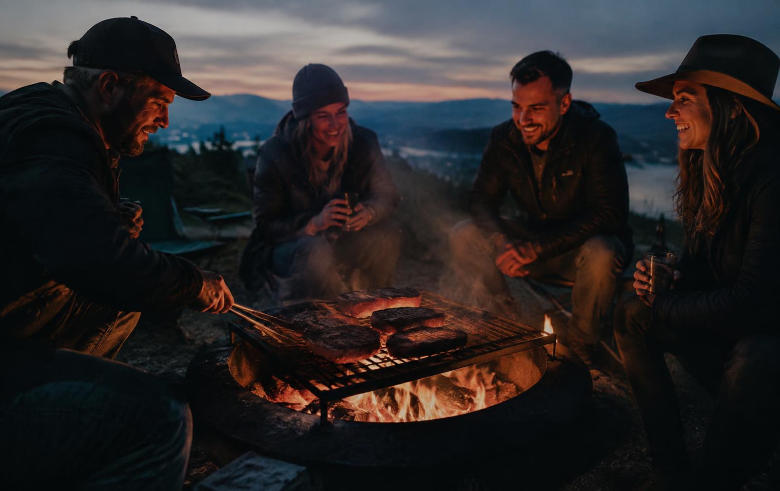 Freunde grillen am Feuer bei Dämmerung